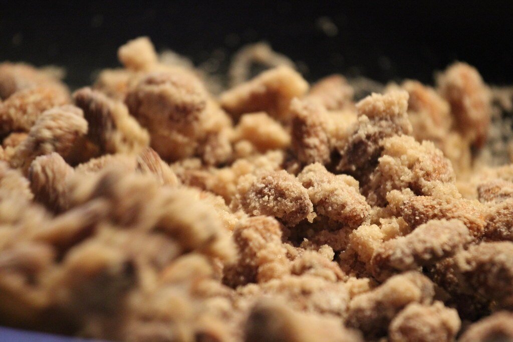 Piccoli dolcetti di mandorle a forma di fava, bianchi, rosa e marroni, in un vassoio