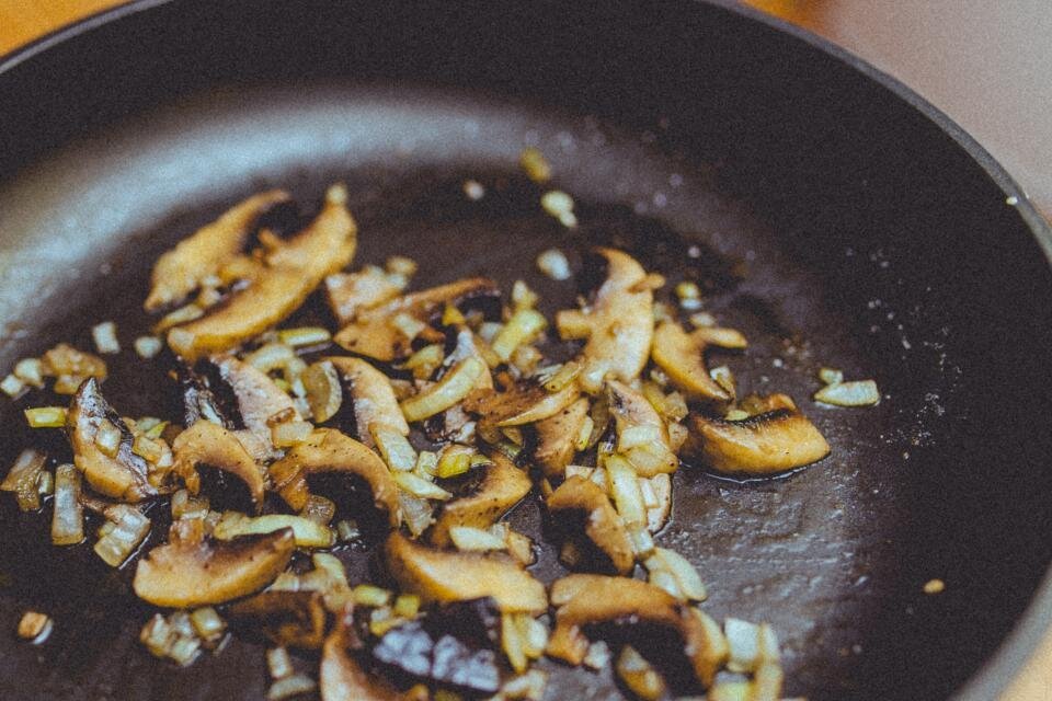 Polenta gialla con funghi trifolati e pezzi di salsiccia in un piatto